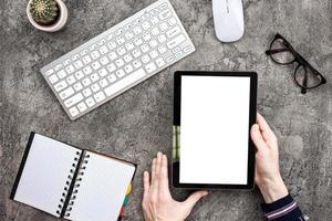 fond de plâtre vue de dessus avec tablette dans la main masculine. clavier, lunettes et cahier ouvert photo