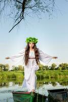 Jeune femme avec fleur couronne sur sa diriger, relaxant sur bateau sur rivière à le coucher du soleil. concept de femelle beauté, du repos dans le village photo