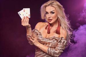 blond femme avec une parfait coiffure et brillant maquillage est posant avec en jouant cartes dans sa mains. casino, poker. photo