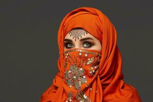 studio coup de une Jeune charmant femme portant le terre cuite hijab décoré avec paillettes et bijoux. arabe style. photo