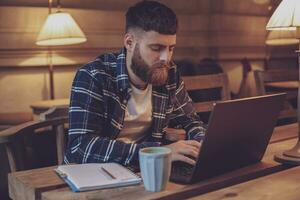 Jeune professionnel surfant le l'Internet sur le sien portable dans une café photo