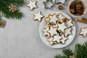 Noël traditionnel allemand biscuits, cannelle étoiles avec noisettes, décoration et arbre branches sur une lumière béton Contexte. Haut voir. copie espace. photo