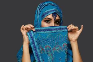 studio coup de une Jeune magnifique femme portant le bleu hijab décoré avec paillettes et bijoux. arabe style. photo