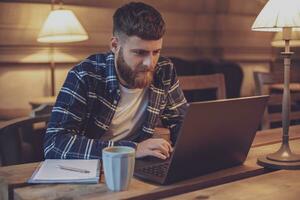 Jeune professionnel surfant le l'Internet sur le sien portable dans une café photo