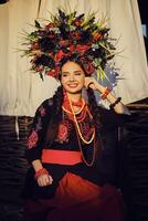 brunette fille dans une blanc ukrainien authentique nationale costume et une couronne de fleurs est posant contre une terrasse. fermer. photo