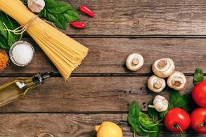 Pâtes Ingrédients - tomates, olive huile, ail, italien herbes, Frais basilic, sel et spaghetti sur une en bois Contexte avec copie espace, horizontal, Haut vue photo