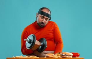 âge moyen homme avec barbe, habillé dans une rouge col roulé, Bandeau, posant avec des hamburgers et français frites. bleu Contexte. fermer. vite aliments. photo