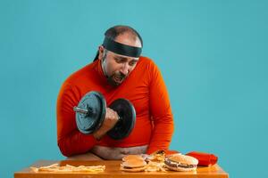 âge moyen homme avec barbe, habillé dans une rouge col roulé, Bandeau, posant avec des hamburgers et français frites. bleu Contexte. fermer. vite aliments. photo