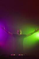 dj à travail mélange du son sur sa ponts à une fête ou nuit club avec coloré fumée lumière Contexte photo