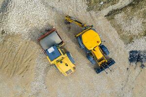 étourdissant aérien vue de le arrêté Jaune excavatrice et tambour rouleau à une construction site photo