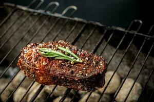 chaud épicé steak grillage sur une été barbecue plus de le chaud charbons garni décoré avec une branche de Romarin photo