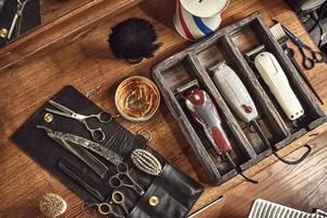 coiffeur outils sur en bois Contexte. Haut vue sur en bois table avec ciseaux, peigne, brosses à cheveux et pinces à cheveux, tondeuse. photo