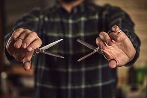 homme coiffeur dans une plaid chemise en portant une tranchant professionnel ciseaux. fermer photo