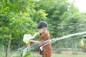 asiatique garçon arrosage les plantes dans Extérieur zone photo