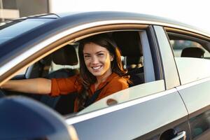 magnifique Jeune femme conduite sa Nouveau voiture à le coucher du soleil. femme dans auto. proche en haut portrait de agréable à la recherche femelle avec heureux positif expression, femme dans décontractée porter conduite une voiture photo