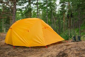 randonnée tourisme aventure. camping pique-nique bleu tente camping dans Extérieur randonnée forêt. touristique bottes près camping tente. site de camp dans la nature à été voyage camp. trekking Voyage vacances concept. photo