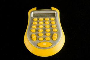 une Jaune calculatrice sur une noir Contexte photo