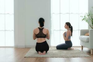 Jeune femme pratiquant yoga avec instructeur dans maison. individuel yoga classe pratiquant dans maison photo