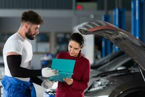 dans un auto réparation boutique, une homme professionnel auto mécanicien slips une femelle client à propos le Coût de voiture réparations et recueille paiement. photo