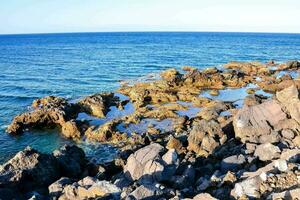 le rocheux littoral de le mer avec bleu l'eau photo