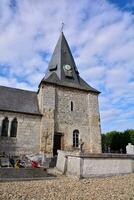 une église avec une l'horloge la tour et une cimetière photo