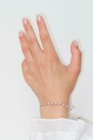 femme main et poignet portant argent zircon scintillait bracelet ensemble contre une blanc Contexte. photo