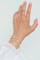 femme main et poignet portant zircon scintillait bracelets ensemble contre une blanc Contexte. photo