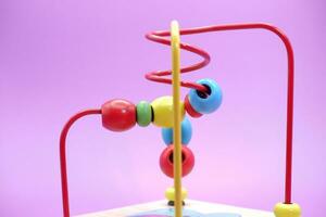 enfants éducatif jouet isolé sur violet Contexte. bambin jouets. jouets avec le fer câble et perles. photo