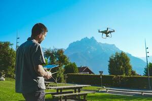 Jeune homme en volant drone sur incroyable Montagne paysage. homme en fonctionnement une drone avec éloigné contrôle prise aérien Photos et vidéos.