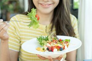 en bonne santé aliments. magnifique femelle fille souriant prendre plaisir manger Frais légume salade sur petit déjeuner santé. content asiatique femme bien émotion. suivre un régime, détox, régime, perdre lester, nettoyer manger, végétarien, nutritionniste photo