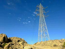 une grand électricité la tour des stands dans le milieu de une rocheux colline photo