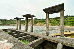 le ruines de une béton jetée sur le plage photo