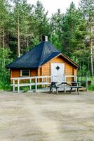 une petit en bois cabine avec une pique-nique table dans le milieu de une forêt photo