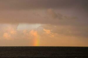 une arc en ciel apparaît plus de le océan dans le distance photo