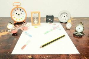 une table avec divers horloges, des crayons et autre articles photo