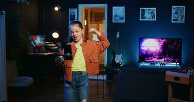 téléphone intelligent sur selfie bâton utilisé par talentueux gen z enfant dans foncé pièce Faire viral Danse chorégraphie, création contenu à produire vues et engagement de autre en ligne les enfants photo