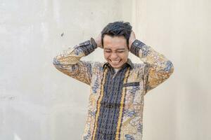 Jeune indonésien porter batik traditionnel culture Indonésie avec frustration geste photo