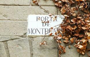 porte de Mont blanc rue plaque, rue signe avec séché feuilles sur un vieux pierre mur, poble espagnol, Barcelone, Espagne. sélectif se concentrer. photo