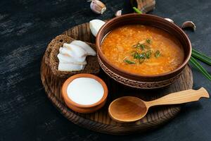 chou soupe dans bol avec vert oignon, pain et salo sur foncé Contexte photo