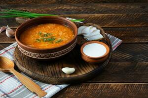 chou soupe dans bol avec vert oignon, pain et salo sur en bois Contexte photo