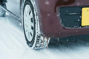 voiture roue pneus sur le route couvert avec neige dans hiver saison, véhicule sur neigeux façon à chute de neige photo