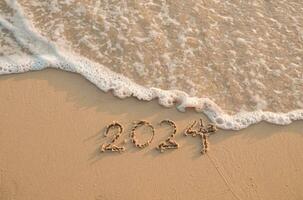 2024 année écrit sur le plage dans le le coucher du soleil temps. Nouveau année 2024 concept photo