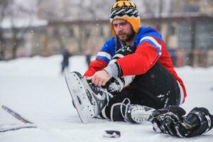 le hockey joueur séance sur le la glace à attacher les lacets photo