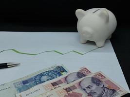 billets de banque croates, stylo et tirelire sur fond avec ligne verte tendance à la hausse