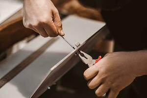 meubles assembleur mécanicien travaux avec Tournevis. Masculin ouvrier installe métal loquet. mains tenir réparation outil. petit affaires soutien. photo