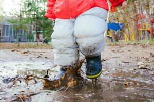 peu enfant sauter dans une flaque dans le parc photo