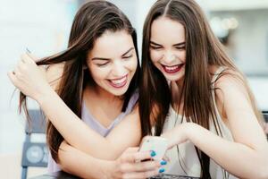 les filles avoir amusement avec une téléphone dans café photo