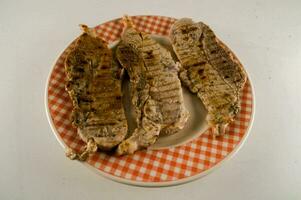 Trois pièces de Viande sur une assiette avec une à carreaux nappe de table photo