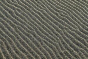 une proche en haut de le sable avec ondulations dans il photo