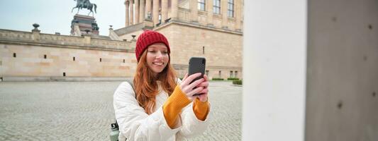 souriant fille touristique prend photo de historique repère, fait du une photo sur téléphone intelligent